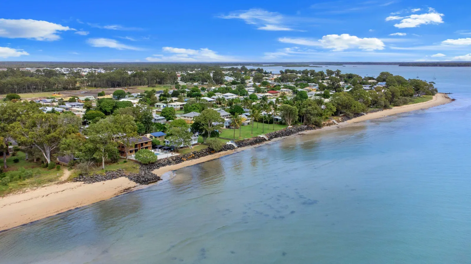 The sandy Burrum Heads foreshore and waterfront homes, photographed from above
