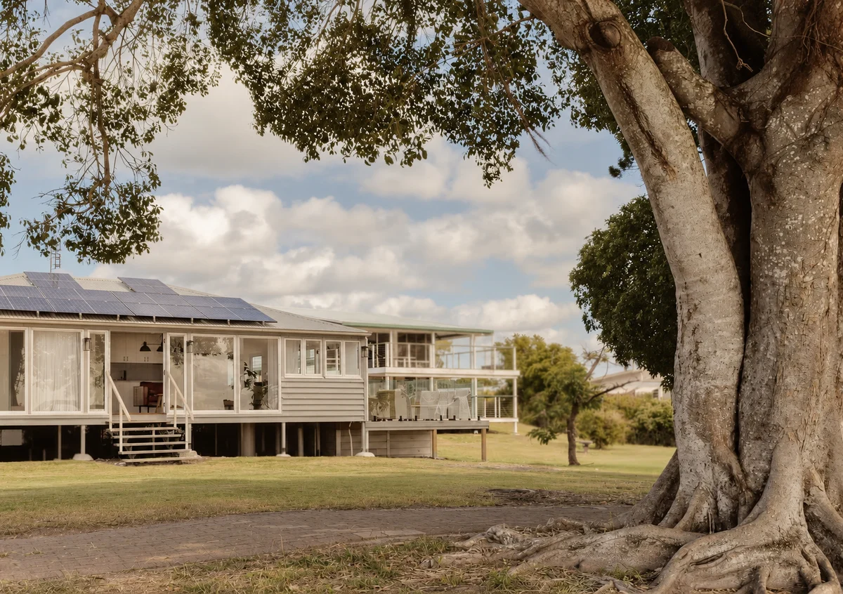 Sunset Waters waterfront house and its verandah beneath riverside trees