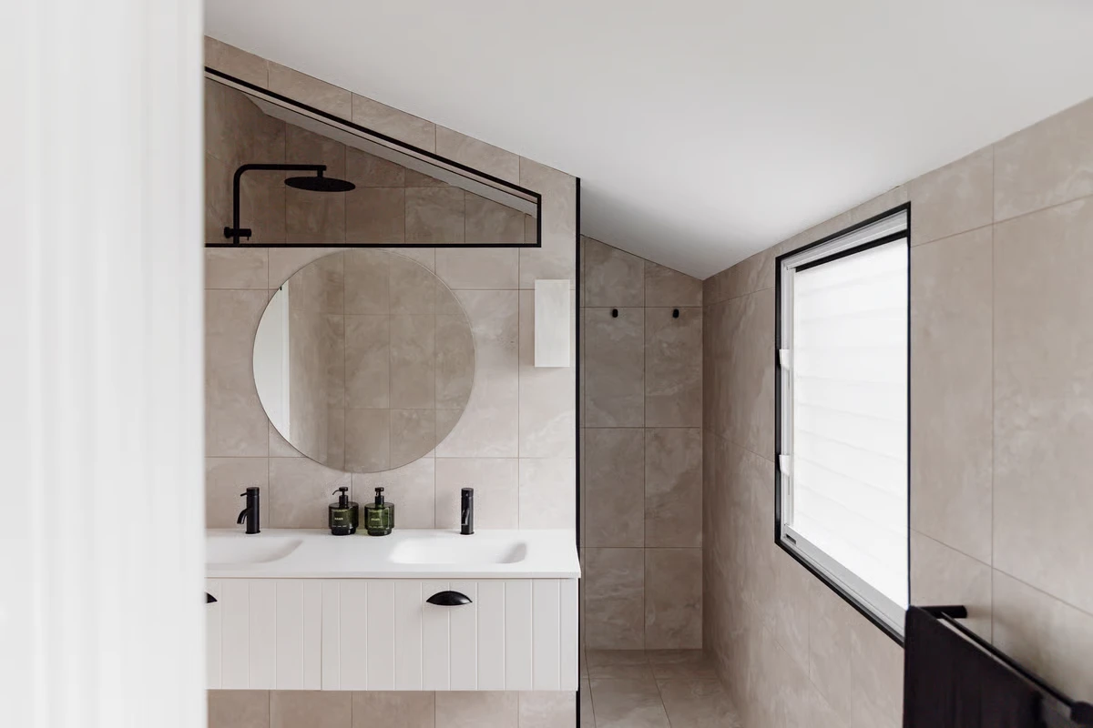 Sunset Waters ensuite bathroom with a round mirror and walk-in shower