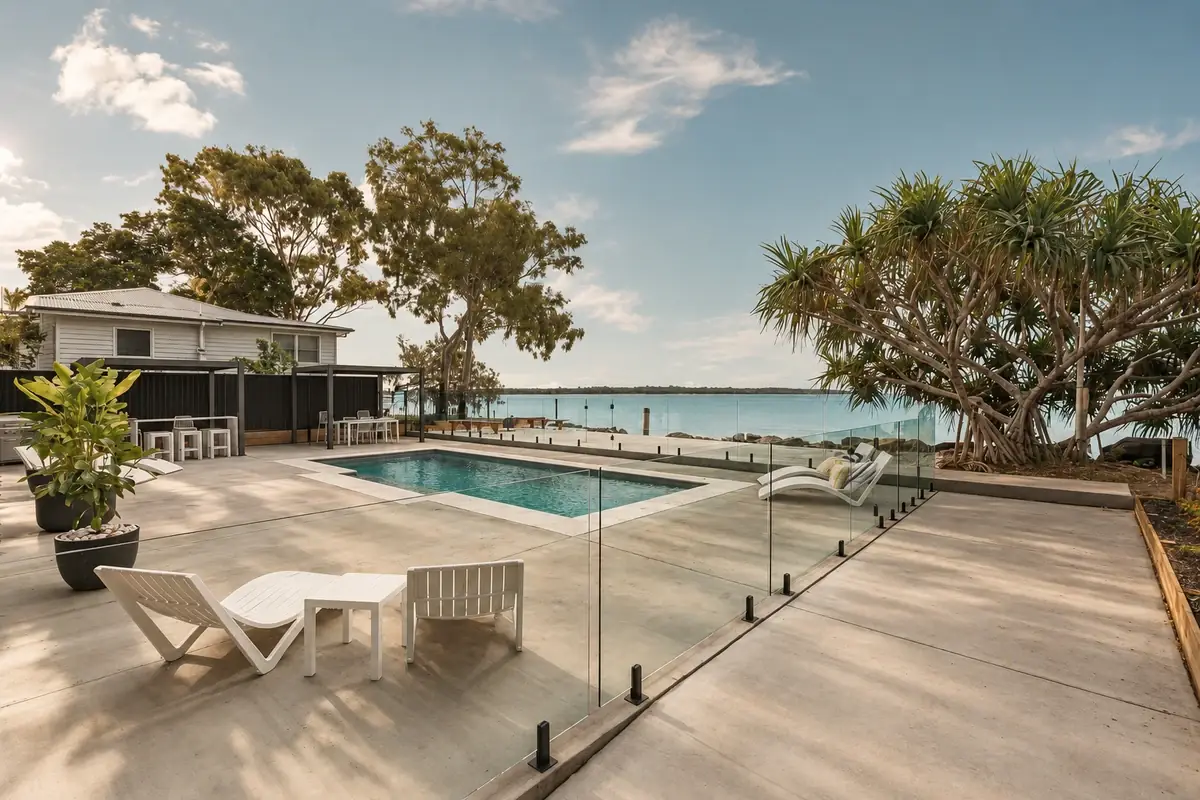 The real Salt and Stone heated pool, concrete terrace, white loungers and pandanus beside the Burrum Heads waterfront