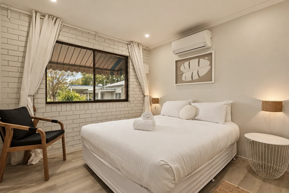 Oceanfront unit bedroom with white bedding and coastal artwork